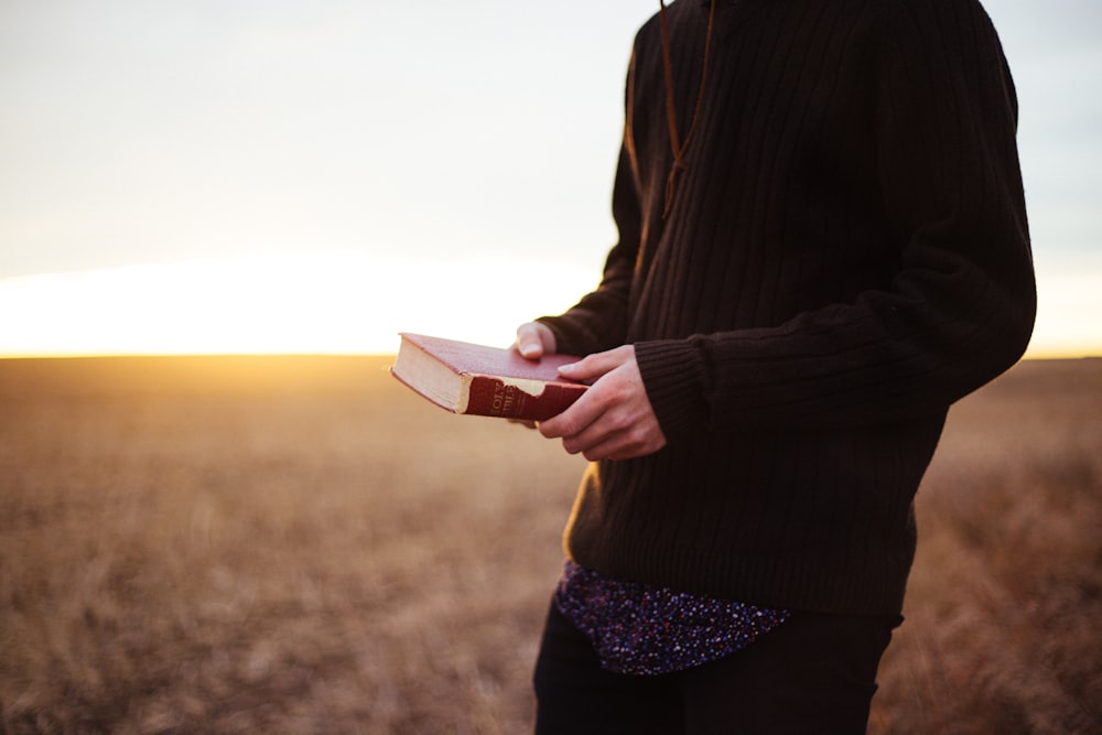 man holding book in the ricefield