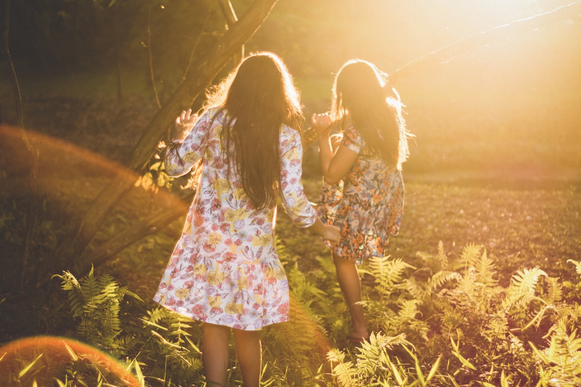 two women running around woods in dresses as sun sets