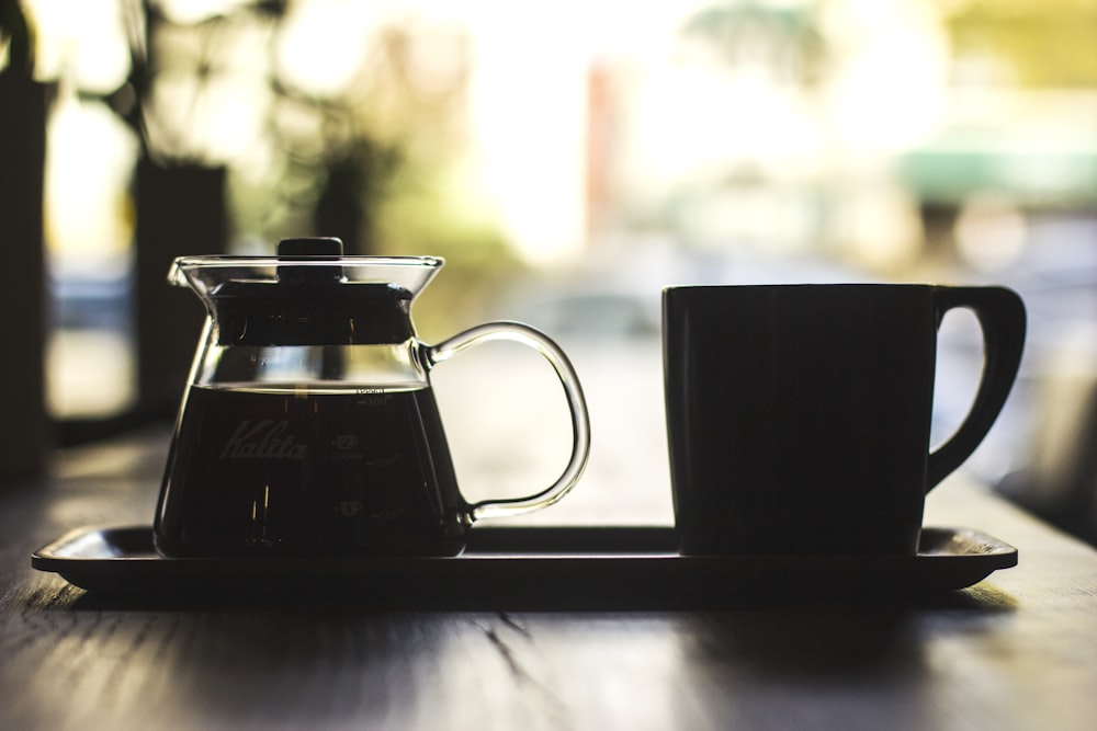 mug and coffee filled carafe on tray at the table