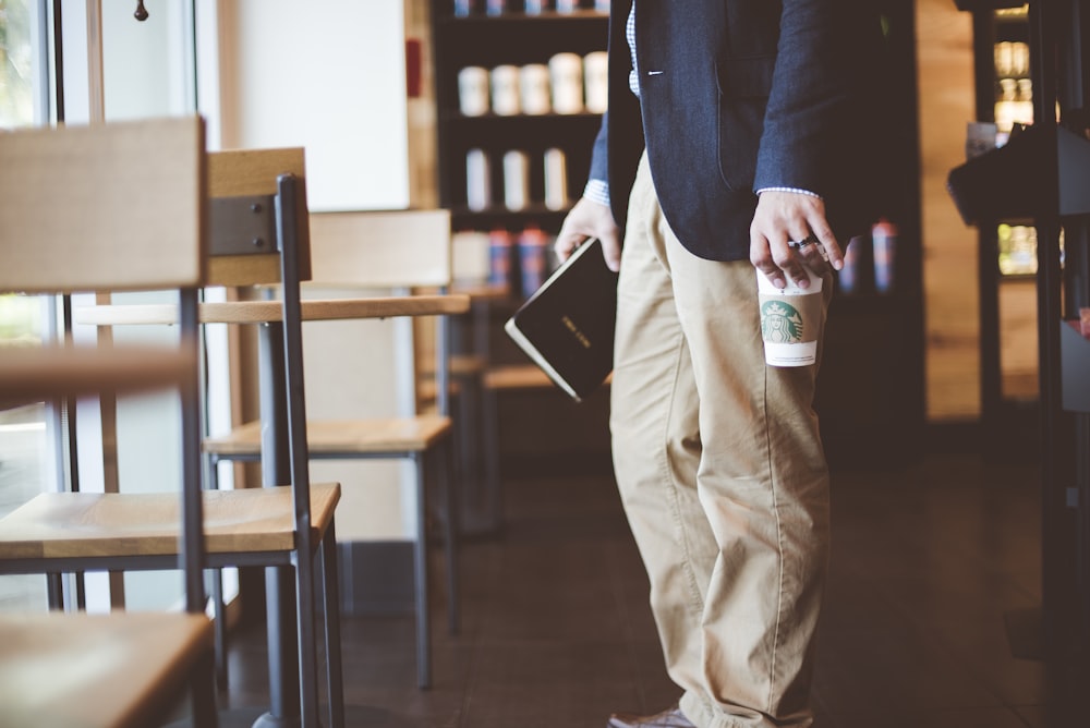 hombre sosteniendo un libro y un vaso de plástico