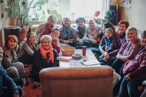 A diverse group of people sitting in a circle sharing stories in a cozy, sunlit room.