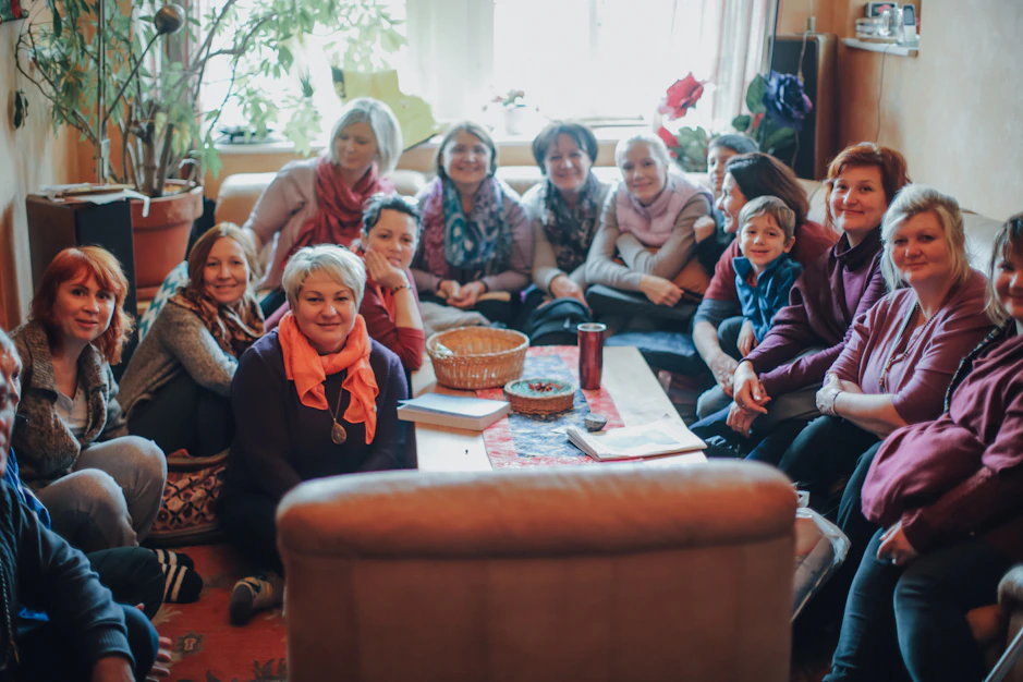A group of diverse women gathered in a warm, sunlit room, sharing stories and supporting each other in faith.
