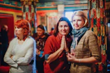 Women concentrating on their mahjong hands in a bright, welcoming event space.