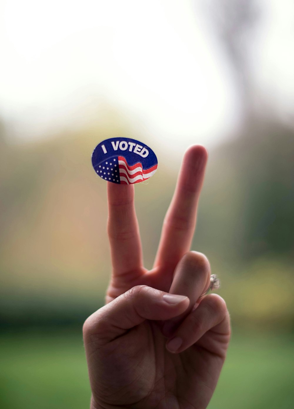 person holding blue and white UNK pin back button