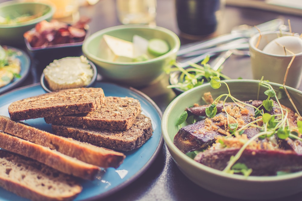 Kitchen table with slices of bread, meat with herbs, and fruit