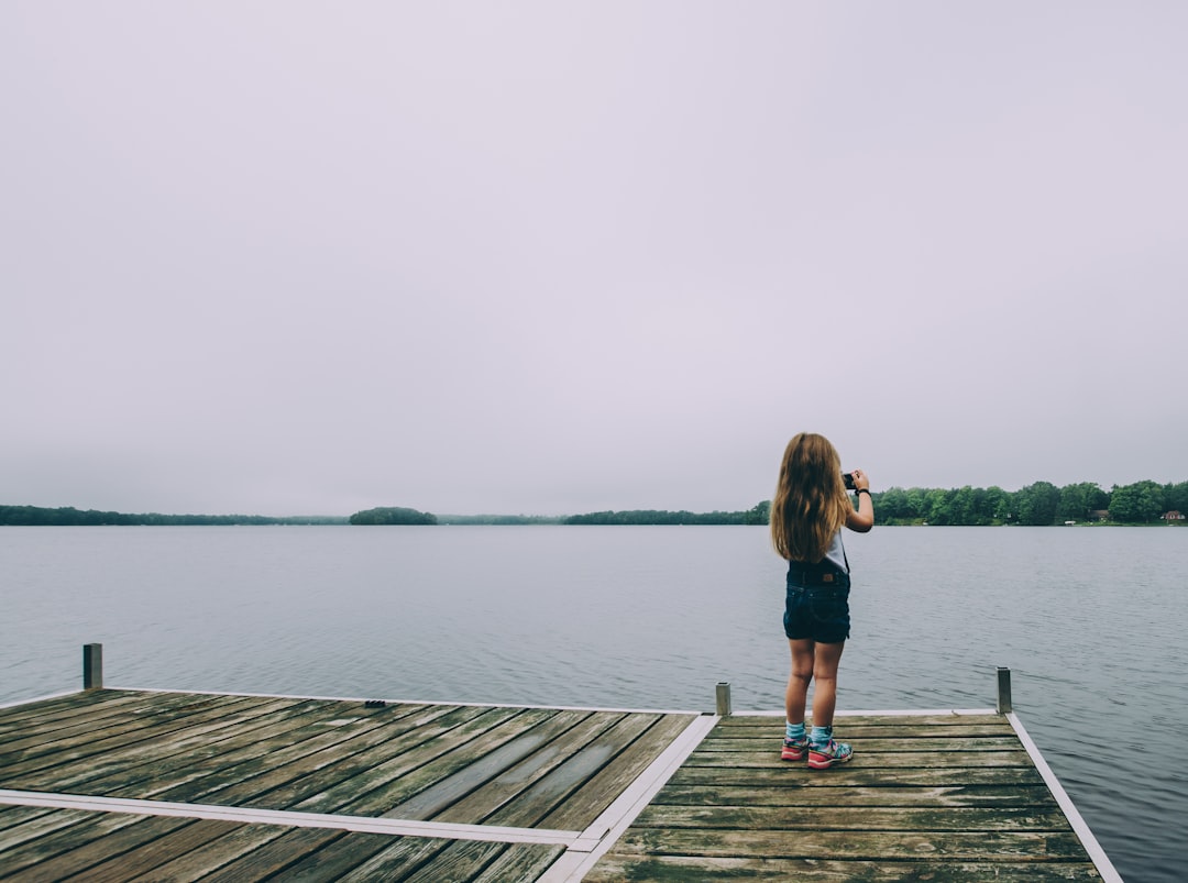 woman standing on brown wooden dock