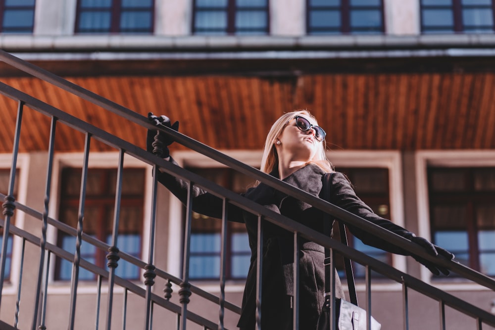 woman standing on stair while holding rails during daytime