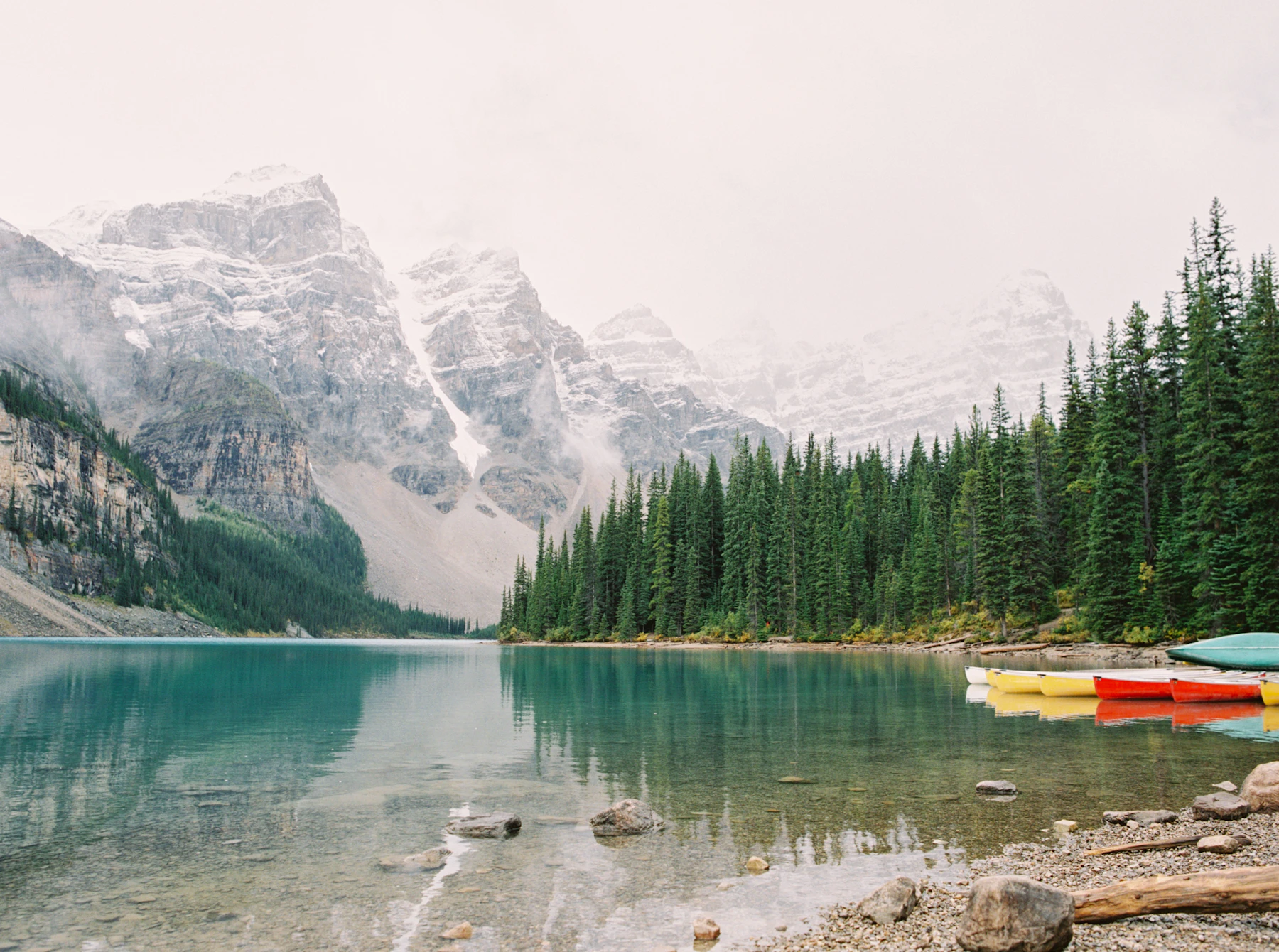 Forest meets water below a mountain ridge.