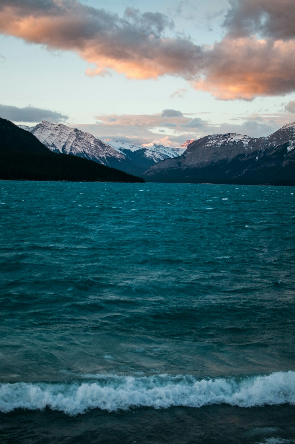 montañas cerca del cuerpo de agua bajo nubes blancas