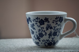 White ceramic mug with a hand-painted floral design on a rustic table.