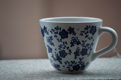 White ceramic mug with a hand-painted floral design on a rustic table.