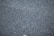A close-up view of a rough asphalt surface, displaying a textured pattern made up of small, irregularly shaped stones and gravel.