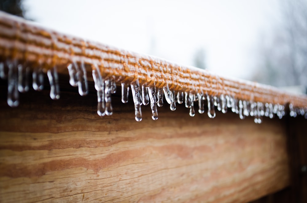 icicles forming at the edge of wooden panel