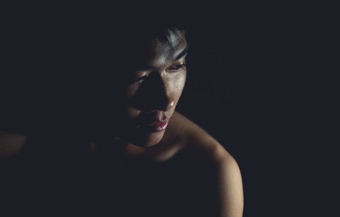 A moody cinematic portrait of a person in low light with dramatic shadows.