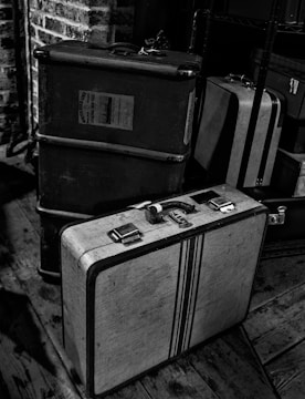 A vintage suitcase with travel stickers from various countries, placed on a wooden floor near a window with soft sunlight.