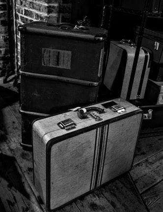 Stacked vintage suitcases and old trunks in a cozy attic space.