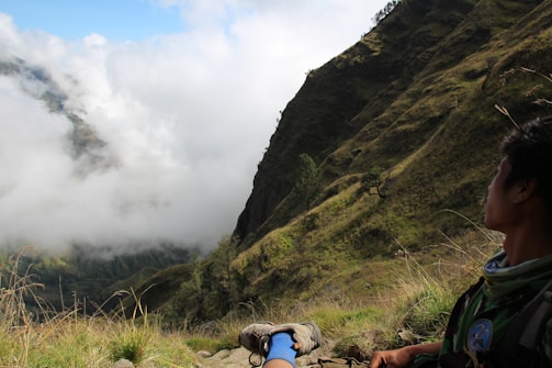 A traveler resting on a sunlit hill overlooking a valley.
