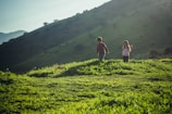 2 women walking on green grass field during daytime