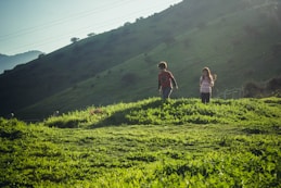 2 women walking on green grass field during daytime
