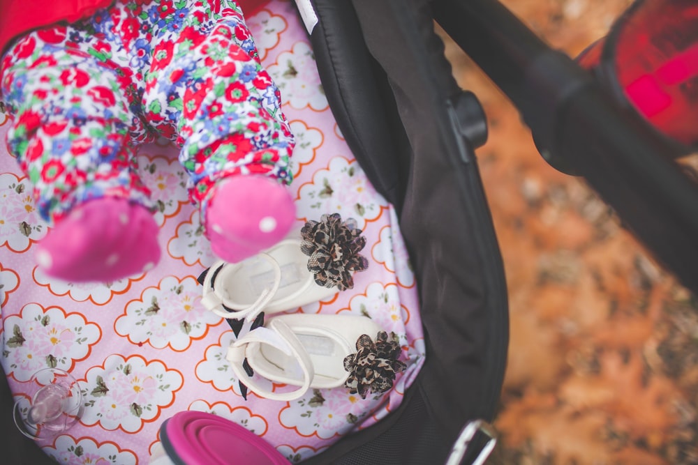 pair of white crib shoes on pink and black stroller