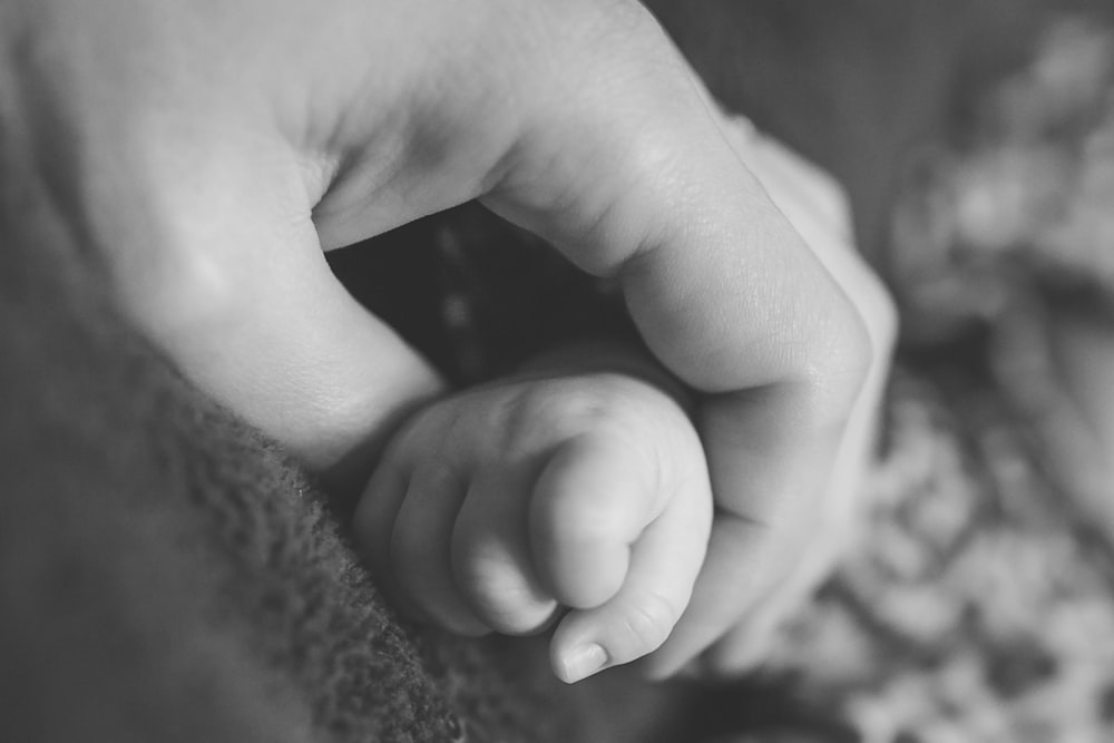 Black and white photo of mother holding child's hand