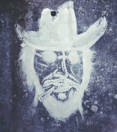 A monochromatic graffiti drawing on a textured wall depicting a person's face wearing a wide-brimmed hat and sunglasses, with a cigarette in their mouth. The art style is rough and sketch-like, focusing on bold outlines and minimal detail.
