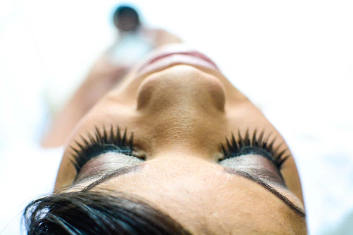 Close-up of a client smiling with beautifully done natural eyelash extensions in a soft, elegant studio setting.