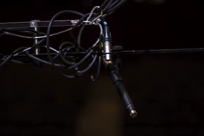 Close-up of a microphone wrapped in cables against a dark backdrop.