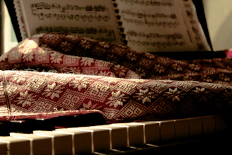 Artistic shot of piano sheet music alongside handcrafted art pieces.