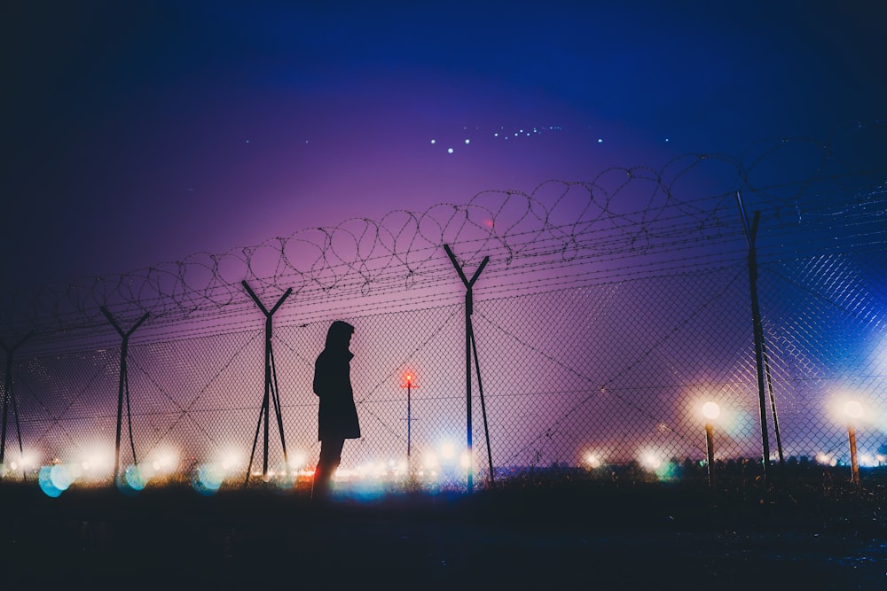 person's silhouette standing near chain link fence