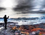 A vibrant portrait of a smiling student photographing a glacier in Alaska during golden hour.