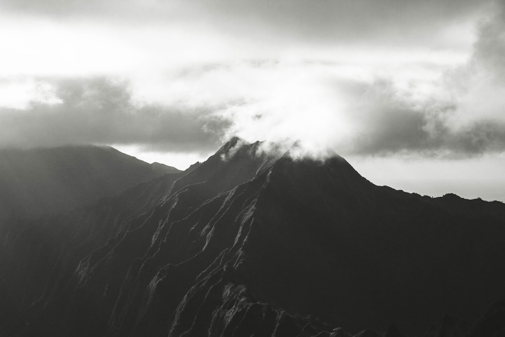 A black and white photo capturing the sun rising over a mountain in Hawaii.