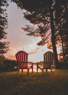 A classic Adirondack chair placed beside a tranquil garden pond during sunset.
