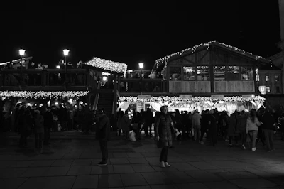 A group enjoying a lively local food market under string lights.