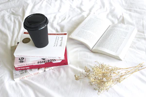A stack of digital books on a wooden desk with a cup of coffee.