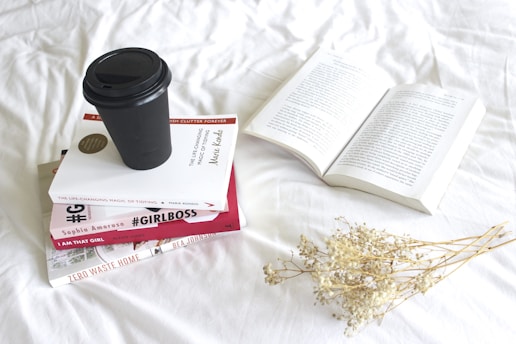 A stack of books on a wooden table with a laptop and a cup of coffee, symbolizing research and writing.