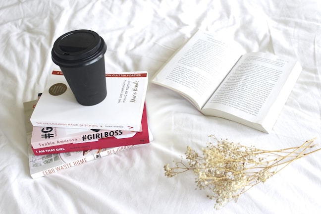 A close-up of a cup of coffee next to a stack of books.