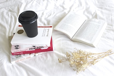 A stack of colorful ebooks on a modern desk with a cup of coffee.