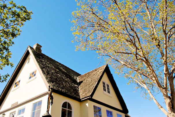 After restoration shot showcasing the same house with a brand new roof and open, inviting windows.
