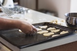 person lining assorted-shaped cookies on baking sheet inside kitchen
