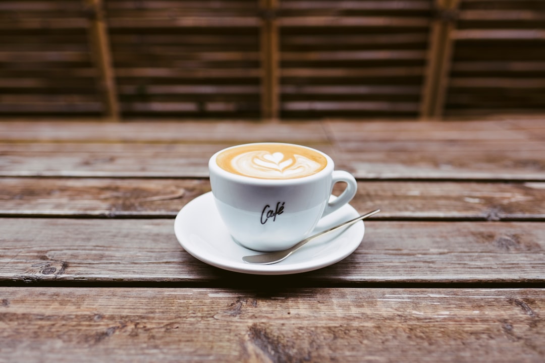 coffee latte on white ceramic saucer beside spoon