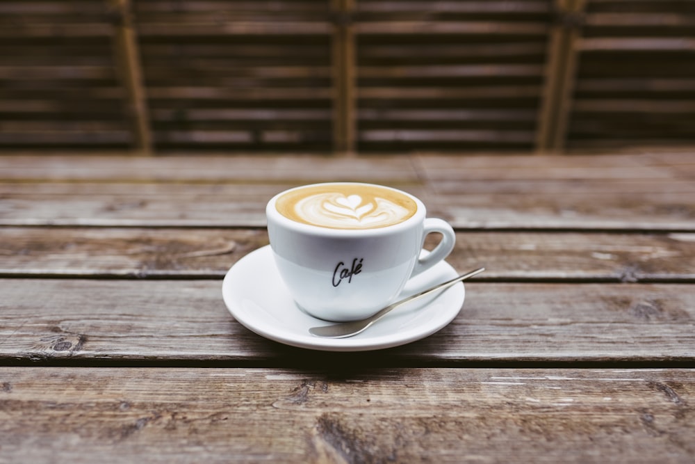 coffee latte on white ceramic saucer beside spoon