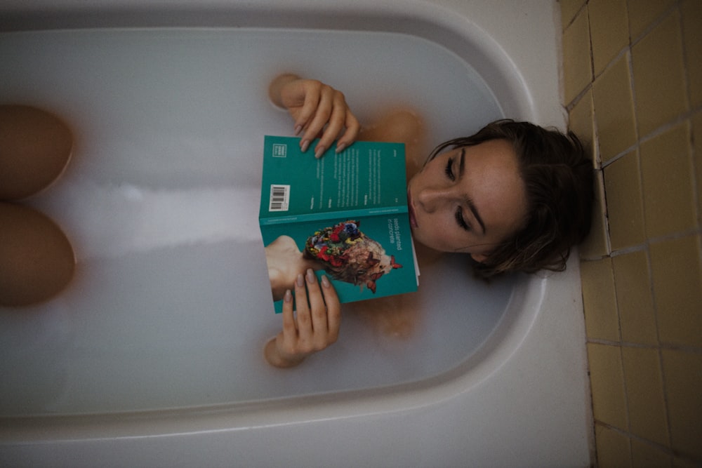 femme allongée sur la baignoire avec le livre vert