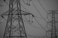 Large metal transmission towers connected by a complex network of power lines. The weather is clear, and the image is in black and white, focusing on the structures' intricate lattice designs.