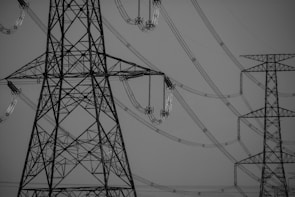 Large metal transmission towers connected by a complex network of power lines. The weather is clear, and the image is in black and white, focusing on the structures' intricate lattice designs.
