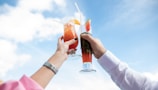 A close-up of hands holding colorful cocktails with garnishes.