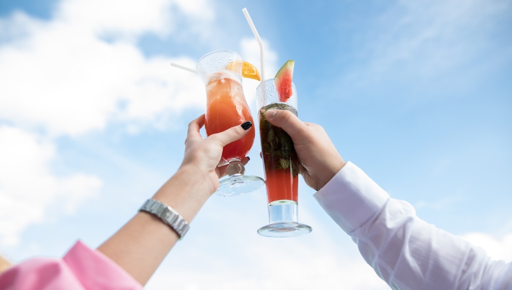 two person holding clear drinking glasses