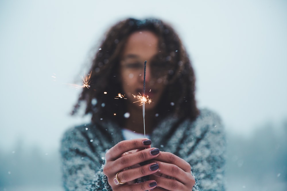 Fotografia a fuoco selettiva di una persona che tiene in mano una stella filante illuminata