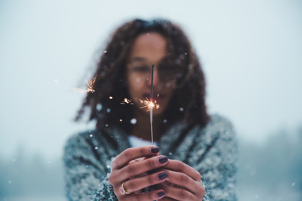 Selektive Fokusfotografie einer Person, die eine beleuchtete Wunderkerze in der Hand hält