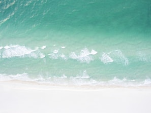 Aerial view of a serene beach with turquoise waters and white sand.